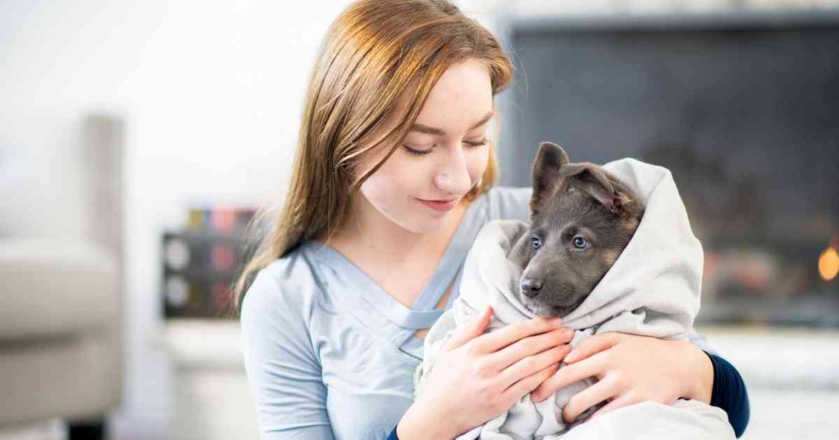 woman warming a puppy